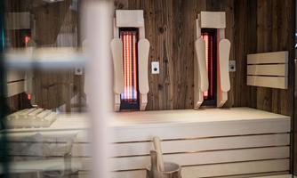 A modern wellness area with wooden paneling. Infrared heaters are installed on the wall, emitting a warm light.