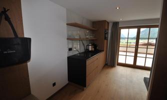 A modern room with a kitchenette and large windows that let in light. The space has a warm wood look and offers a view outside.