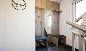 A modern designed entrance area with wooden shelves and seating options. The walls are bright and friendly, and there are windows that let in plenty of light.