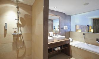 A modern bathroom with an elegant shower and a large sink. The space is bright and well-designed, with a separate toilet.