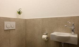 A modern small bathroom with a toilet and a sink. The walls are in neutral colors.