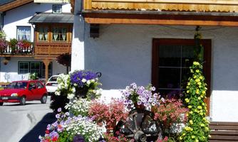 A charming house with a flower-adorned entrance. Colorful flowers and a wooden house sign create an inviting atmosphere.