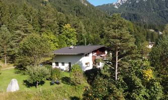 A cozy house surrounded by green trees and mountains. The landscape radiates tranquility and a connection to nature.