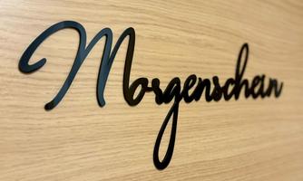 An elegant font with the word "Morgenschein" on a wood-like surface. The design is modern and inviting.