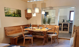 A cozy dining area with a wooden bench and table. The walls are bright and tastefully decorated.