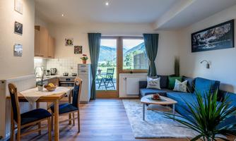 A cozy holiday apartment with a modern kitchen corner and an inviting living area. Large windows provide a beautiful view of the mountains.