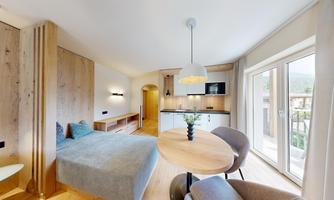 A modern room with a comfortable bed and a small table. Large windows provide plenty of natural light and create an inviting atmosphere.