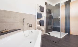 A modern bathroom with a bathtub and a glass shower. Towels are neatly hung on a towel rack.