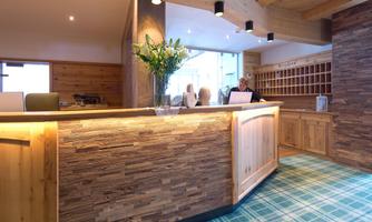 A modern hotel reception made of wood with an inviting ambiance. Fresh plants and a bright, friendly design create a pleasant atmosphere.