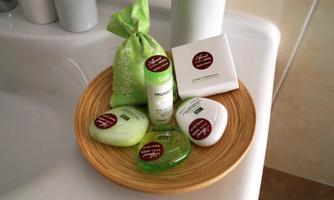 A bowl with various skincare products, including soaps and lotions, on a sink. The products are in green and white tones and decorated with small stickers.