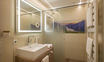 A modern bathroom with a shower and washbasin. Large mirrors and a panoramic wall design create an inviting atmosphere.