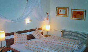 A cozy bedroom with two beds and decorative cushions. Soft light creates a relaxed atmosphere.