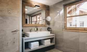 A modern bathroom with an elegant sink and wooden details. Large windows let in plenty of daylight.