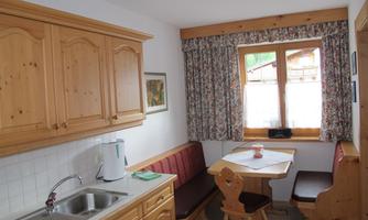 A cozy kitchen with wooden furniture and a dining area. A window lets in plenty of light and a view of the outside.