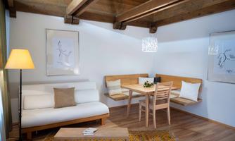 A modern living room with wooden ceilings and a cozy sofa. The table and seating provide space for social gatherings.
