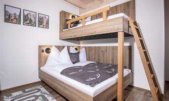 A modern bedroom with a loft bed and a double bed. The walls are decorated with minimalist pictures.