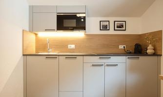 A modern kitchen with a wood and gray surface combination. The lighting creates a pleasant atmosphere.