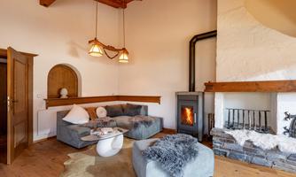 A cozy living room with a modern fireplace and comfortable furniture. There is a warm atmosphere with wooden flooring and stylish decorations.