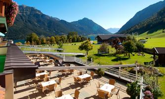 A beautiful view of the mountains and a clear lake. The terrace is equipped with tables and chairs and invites you to linger.