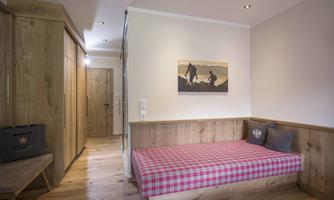 A cozy room with wooden paneling and a red checkered fabric. A seating area with light cushions and a piece of art on the wall complements the atmosphere.