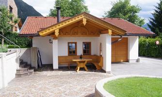 A beautiful, traditional house with bright wooden decorations. The entrance area features a cozy bench and a paved floor.