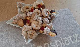 A pretty star-shaped dish with various cookies and sweet treats. The table is made of wood and creates a cozy atmosphere.