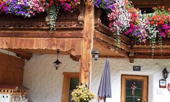 A traditional house with colorful flowers on the balcony. Below is a cozy seating area with a table and chairs.