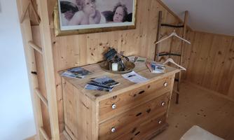 A wooden dresser in a bright room with wooden walls. On the dresser are brochures and a decorative vase.