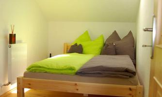 A cozy bedroom with a wooden bed and colorful pillows. A skylight lets in plenty of light.