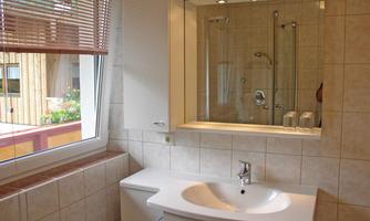 A modern bathroom with a sink and a large mirror. The window lets in plenty of daylight and offers a view outside.