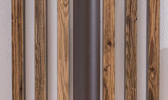 An elegant lamp hangs on a wooden slat wall. The combination of brown and wood gives the room a warm atmosphere.