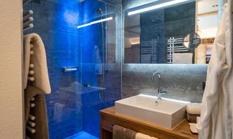 A modern bathroom with a glass shower and stylish vanity. Soft towels and discreet lighting create a cozy atmosphere.