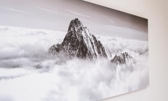 An impressive mountain rises from the clouds. The black-and-white depiction enhances the majestic atmosphere of the scene.