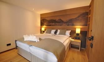 A cozy bedroom with two beds, wood paneling, and warm lighting. The atmosphere is modern and inviting.