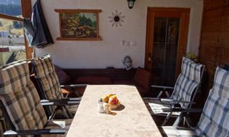 A cozy terrace with a large, round table and comfortable chairs. Fresh apples and a small decoration are on the table.