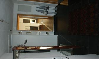 An inviting hallway with a dark floor and bright walls. In the background, an open living and kitchen area is visible.