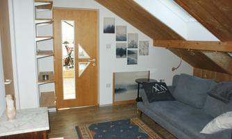 A cozy passage room with a gray (sleeping) sofa and large skylights.