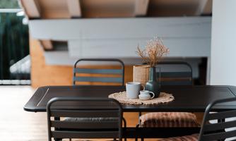 A stylish table with chairs, decorated with a tablecloth and a vase. On the table are cups and a decorative bowl.