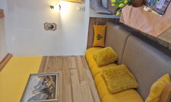 A cozy seating area with a gray sofa and yellow cushions. On the table sits a vase with fresh tulips.