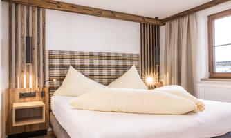 A modern bedroom with a large double bed and wooden paneling. Bright colors and a cozy atmosphere create an inviting ambiance.