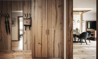 A modern, stylish room with wood paneling and an open concept design. The hallway leads to an inviting dining area and a cozy living area.