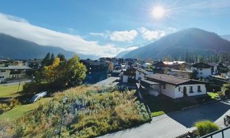A picturesque mountain landscape with houses and clear air. The sun shines over the mountains and the clouds.