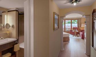 An elegant bathroom with modern fixtures and a large mirror. In the background, there is a cozy seating area with a view of a garden.