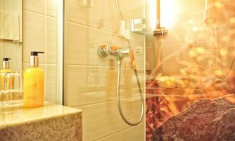 A modern shower with an elegant showerhead. Liquid soaps in stylish bottles are on the sink.