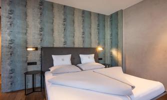 A modern bedroom with a double bed and stylish pillows. The walls are painted in soft colors, creating a relaxing atmosphere.