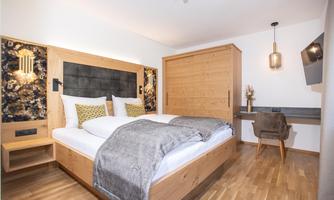 A modern room with a double bed and a cozy decor. The room has wooden flooring and stylish decorations.