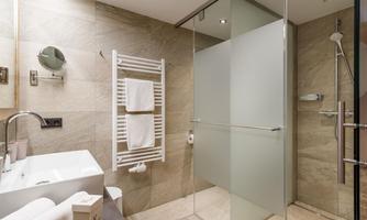 A modern bathroom with a glass shower cabin and elegant tiles. Towels are neatly arranged and there is a stylish vanity unit.