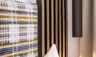 A modern bedroom with a striped headboard and a decorative lamp. The room exudes a calm and stylish atmosphere.