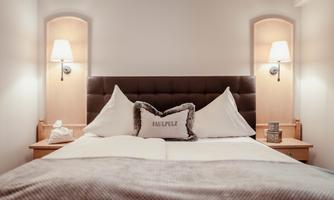 A cozy bedroom with a large bed and soft pillows. Two nightstands with lamps create an inviting atmosphere.