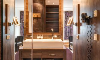 A modern bathroom with an elegant washbasin and warm wooden elements. Bright lighting creates an inviting atmosphere.